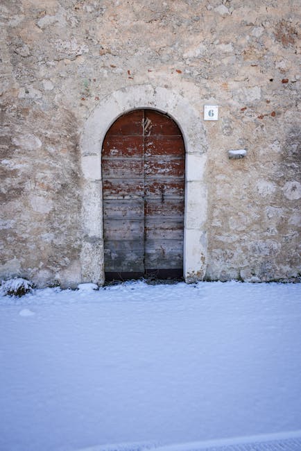 Arched wooden door in stone wall with 6 sign